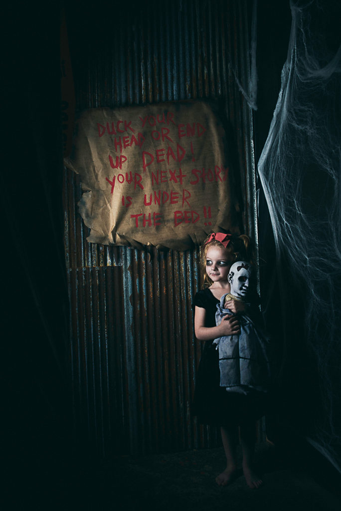 little girl holding a creepy doll in a haunted house doing unique Halloween photos