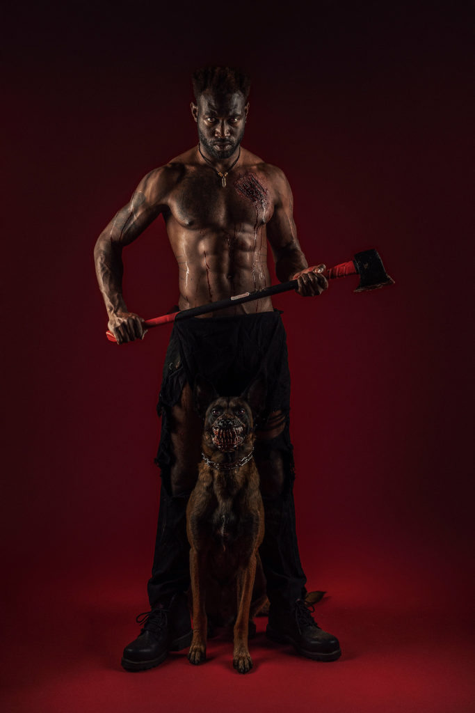unique halloween photo of man holding ax with a dog next to him