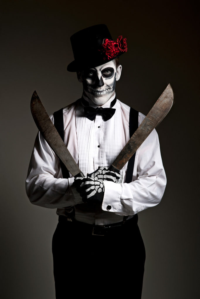unique halloween photo of man holding machetes with face painted
